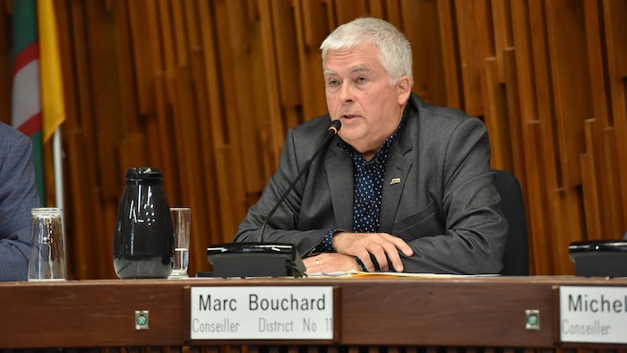 Un homme en complet devant un micro.