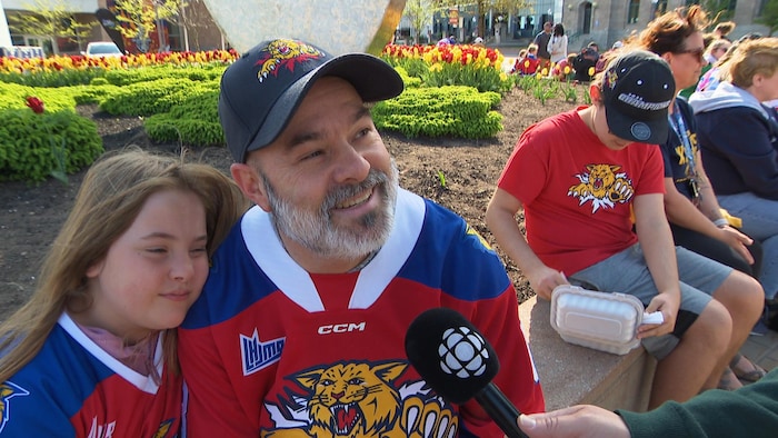 Un homme accompagné de sa fille est interviewé au centre-ville.