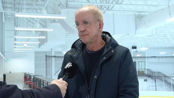 Un homme dans un aréna, un micro de Radio-Canada pointé en sa direction.
