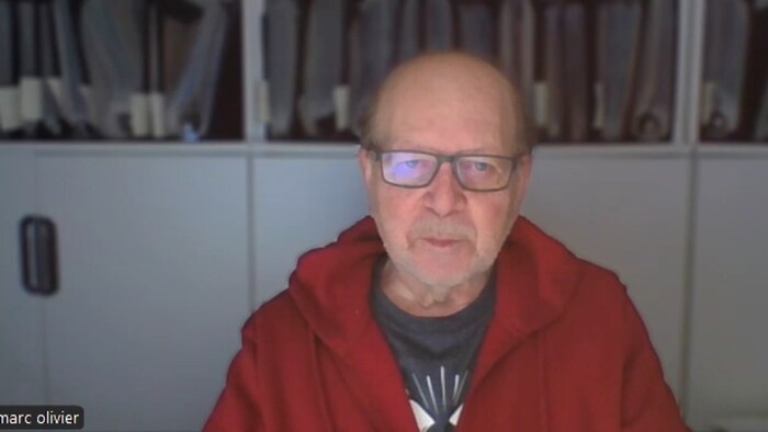 Marc Olivier est assis dans son bureau regardant la caméra de son ordinateur.