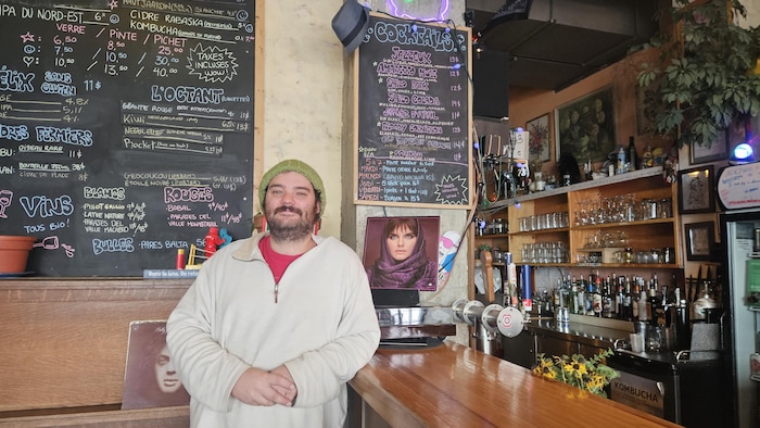 Marc-Olivier Gaudreault pose à côté d'un comptoir de bar près d'une photo dédicacée de Diane Tell.