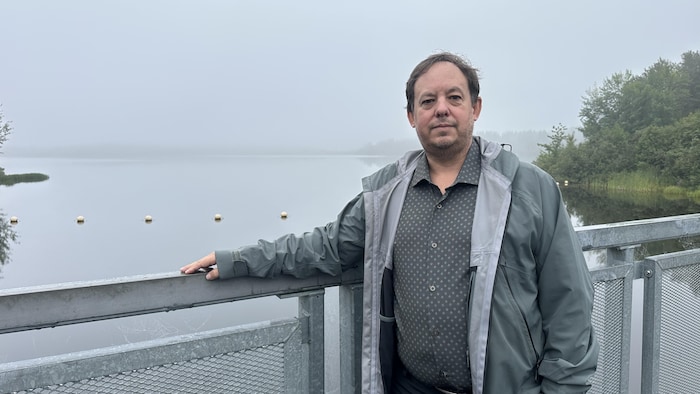 Un homme pose devant un lac embrumé