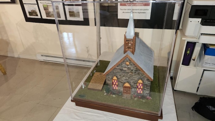 La maquette représente une église calviniste modeste, de petite taille, avec un petit clocher en bois et des vitraux rouges et orange.