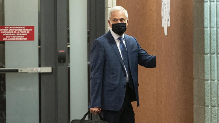 Un homme debout et portant un masque au palais de justice de Montréal.