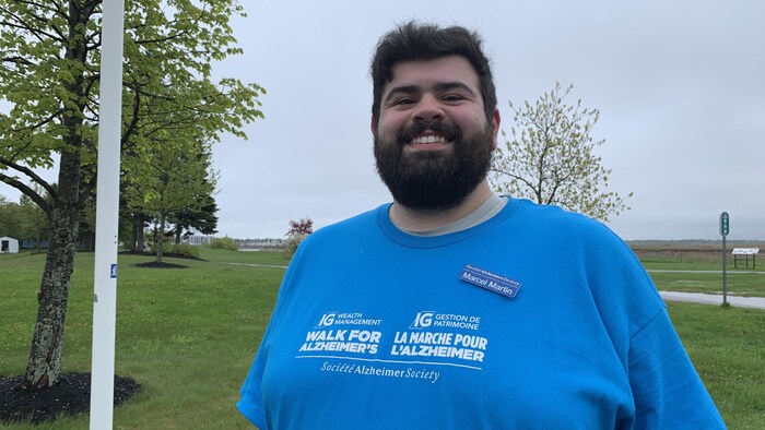 Un homme souriant dehors avec un chandail de la marche pour l'Alzheimer. 