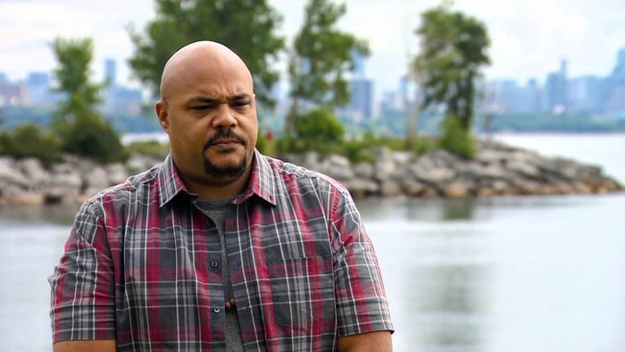 Marcell Wilson debout à l’extérieur devant un lac. Au loin, la vue sur le centre-ville de Toronto.