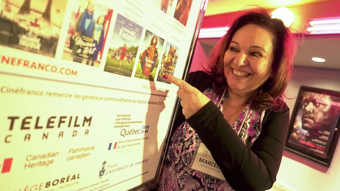 Elle montre une affiche avec les films projetés dans le cadre de l'événement.