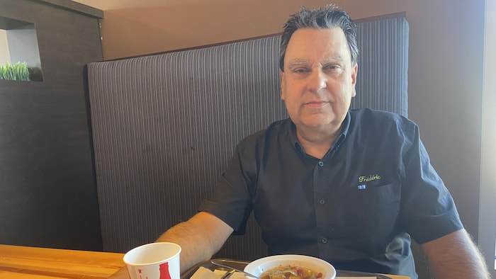 Un homme mange une soupe dans un restaurant.