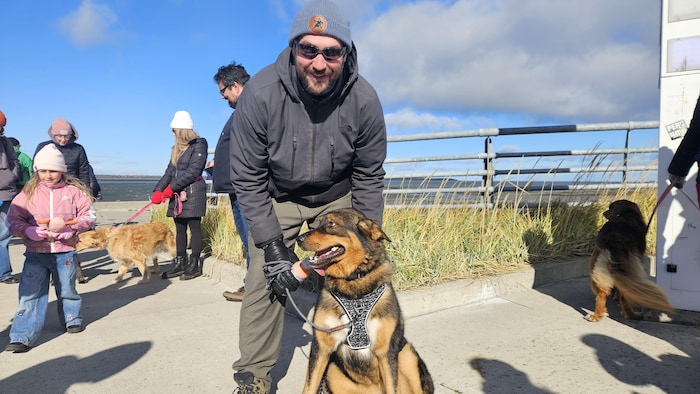 Un homme tient un chien en laisse.