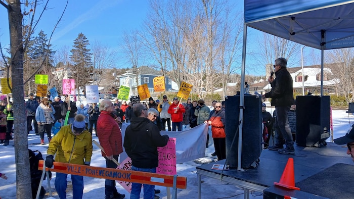 Un intervenant prend la parole au micro devant une petite foule.
