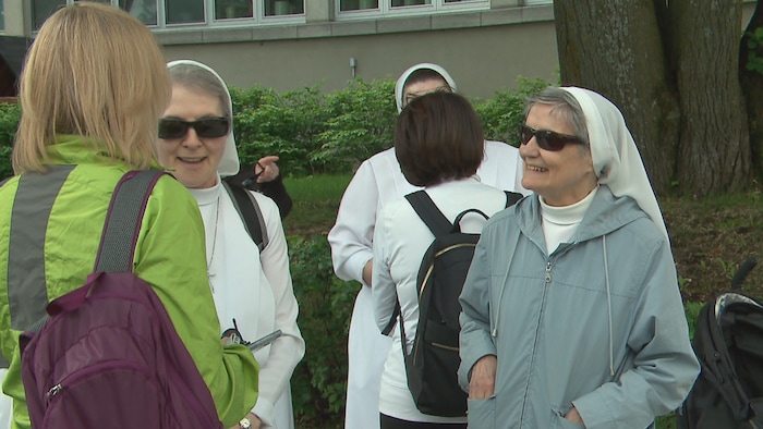 Des religieuses sont regroupées dehors et discutent avec des civils.