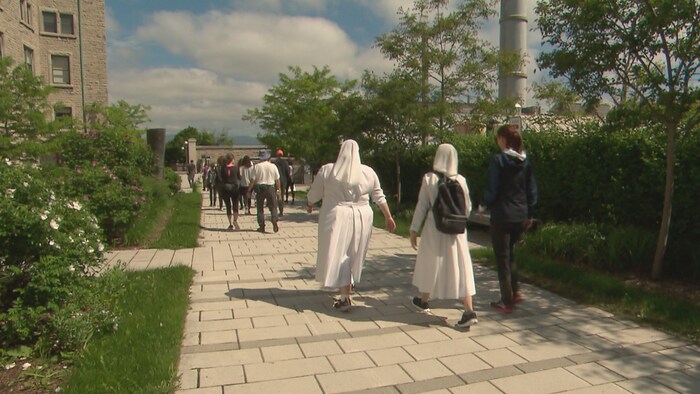 Des religieuses en tenue blanche marchent dans la rue.