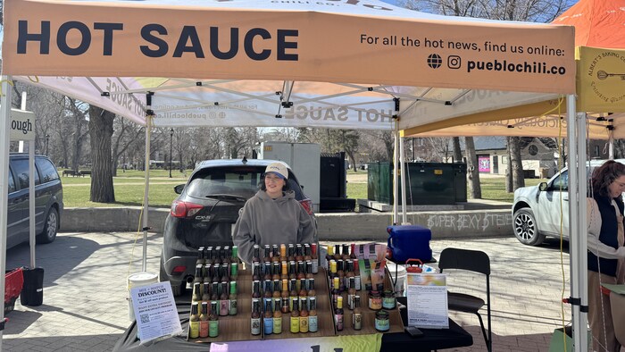 Une personne debout dans un stand de vente de sauces piquantes. 