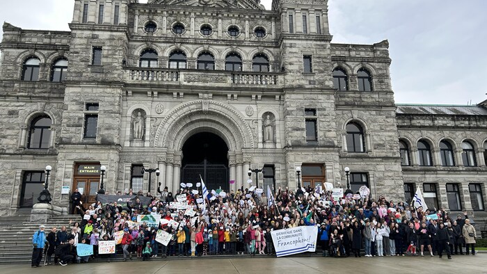 Des gens posent en rang devant l'Assemblée législative de la Colombie-Britannique.