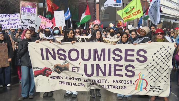 Des personnes portent une banderole qui indique « Insoumises et unies ».