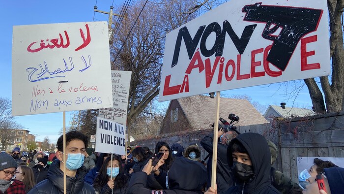 Deux adolescents tiennent deux pancartes au milieu d'une foule.