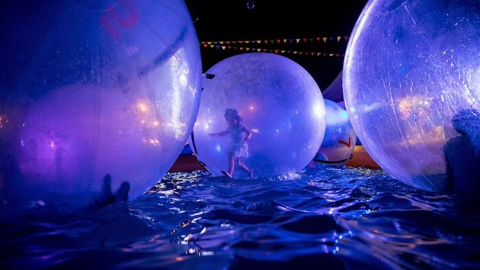 Une petite fille court à l'intérieur d'une boule gonflable permettant de marcher dans l'eau tout en flottant dans une piscine, au marché nocturne de Richmond, le 4 août 2018.