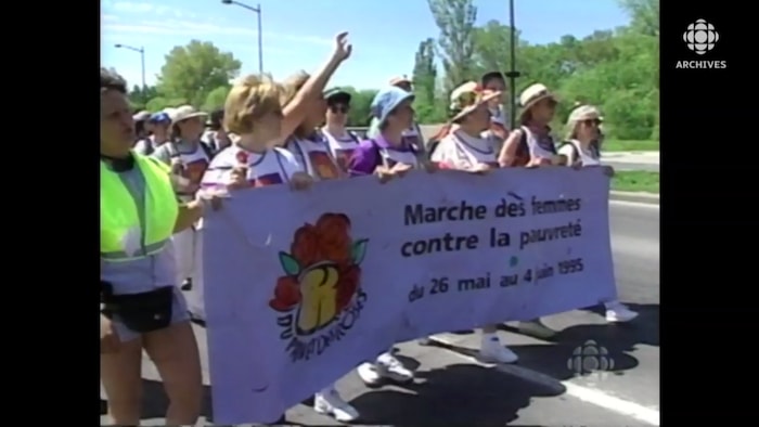 Des femmes avancent en tenant une banderole qui porte l'inscription « marche des femmes contre la pauvreté ».