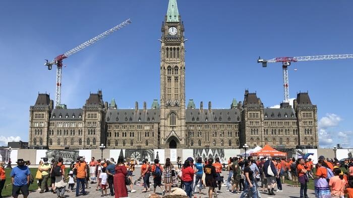 Des personnes réunies devant le Parlement, à Ottawa.
