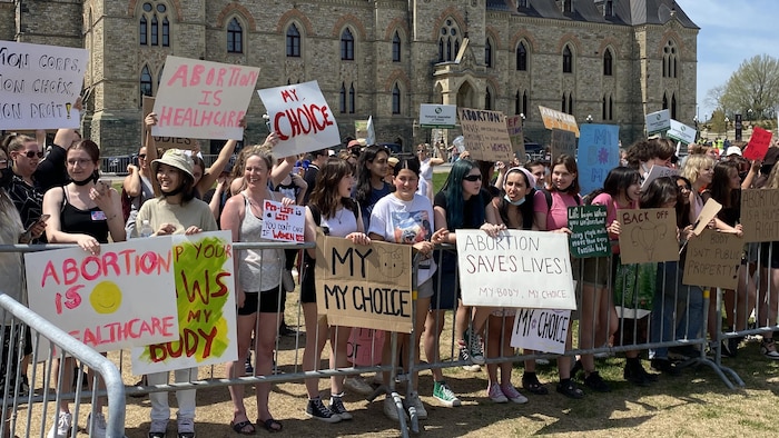 Des contre-manifestants à la Marche pour la vie, à Ottawa, devant le parlement, avec leurs pancartes.
