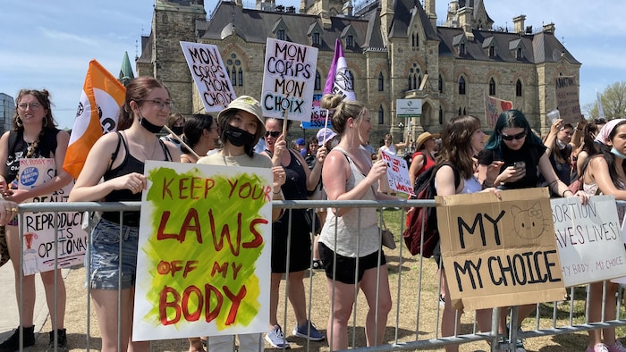 Des contre-manifestants à la Marche pour la vie, à Ottawa, brandissent leurs pancartes.