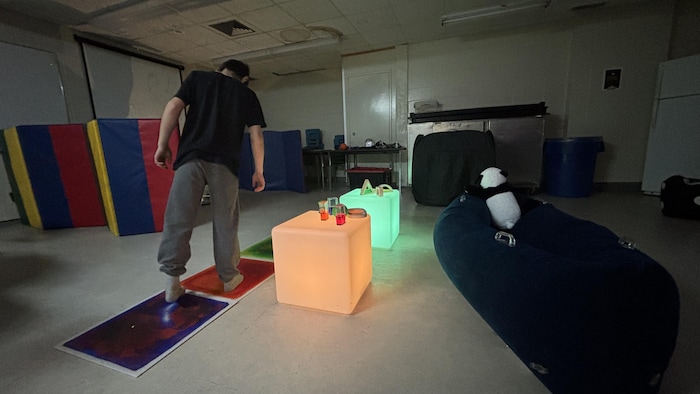 Un espace sombre avec des blocs de couleur, des coussins, des matelas.