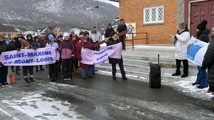 La mairesse fait un discours devant l'église de Mont-Louis, avec un groupe de personnes à l'extérieur.