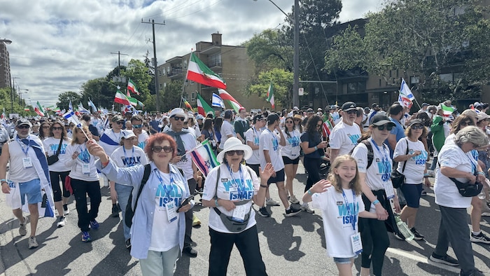Deux femmes et une petite fille envoient la main au milieu de la foule lors de la marche « Walk with Israel ».