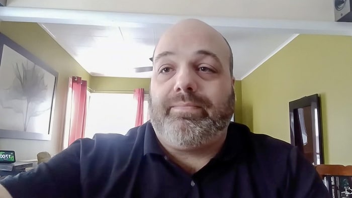 L'homme âgé d'une quarantaine d'année fait une présentation devant un écran.