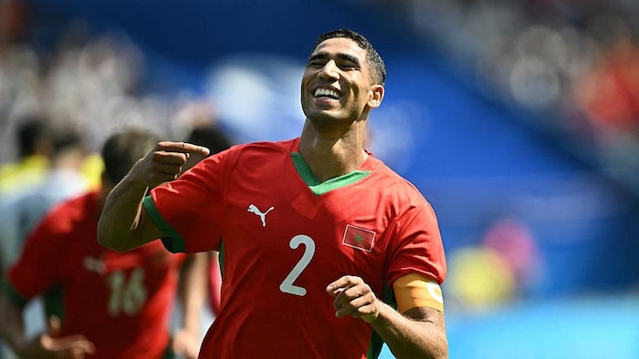 Achraf Hakimi sourit de joie dans un stade après une victoire de son équipe lors d'un match de soccer entre le Maroc et les États-Unis lors des Jeux olympiques de Paris en 2024.