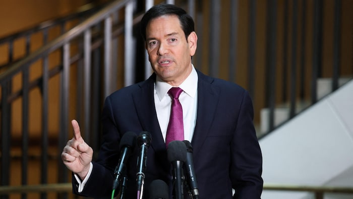 Marco Rubio, près d'un escalier et devant des microphones, parle.