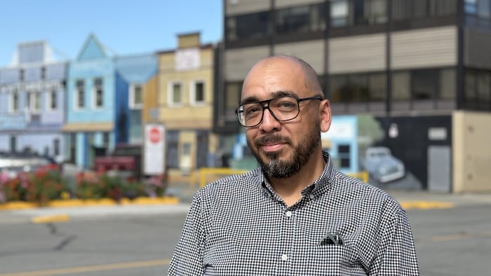Un homme sourit devant une rue de Whitehorse.