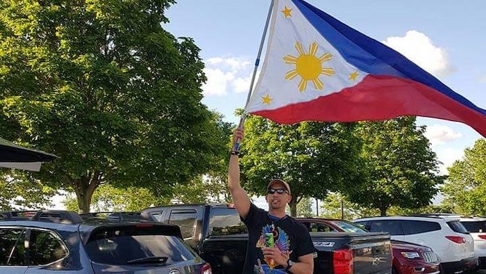 Roberto Rivera hawak ang Philippine flag.