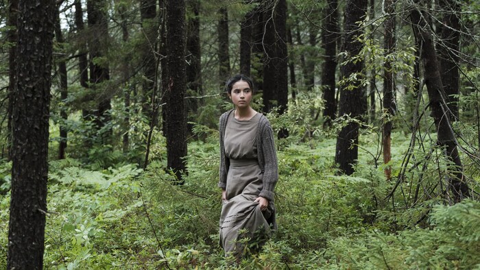 Une jeune femme marche seule en forêt.