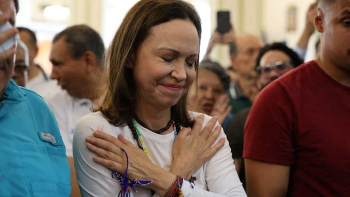 Maria Corina Machado ferme les yeux et place ses mains sur sa poitrine. 