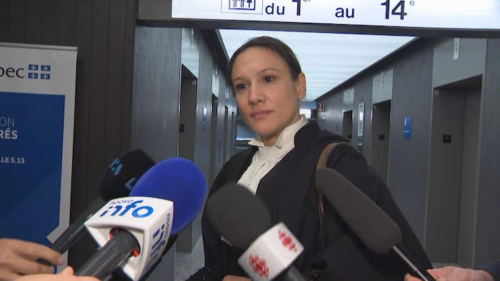 Une avocate en conférence de presse regarde les journalistes.