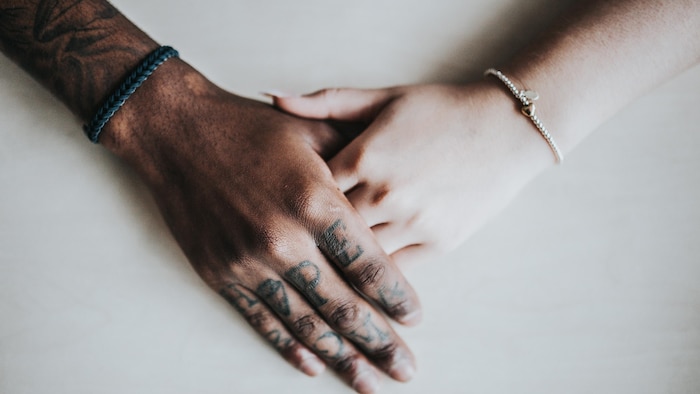 Les mains de deux personnes de couleur de peau différentes qui se touchent.