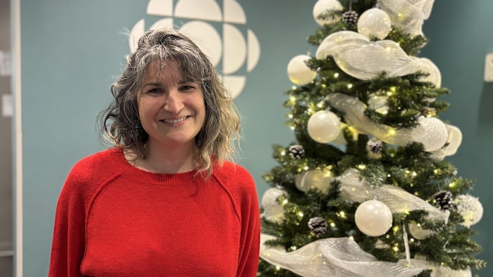 Marianne Creysson souriante devant un arbre de Noël décoré.