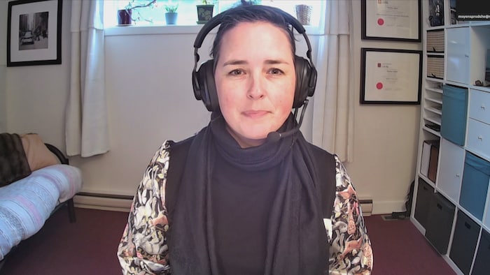 Marianne Gagnier en entrevue en visioconférence à Radio-Canada. Derrière elle, ses diplômes sont accrochés au mur.