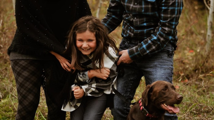 Une famille en automne s'amusent dans la forêt avec leur chien.