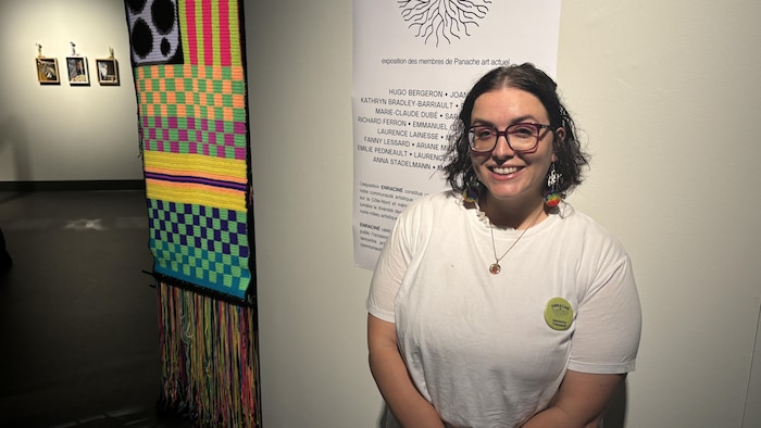 Plan moyen d'une femme portant des lunettes et une chemise claire, souriant à l'appareil photo.