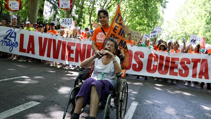 Une femme pousse une chaise roulante où est assise une vieille dame, en ouverture d'une manifestation à Madrid.