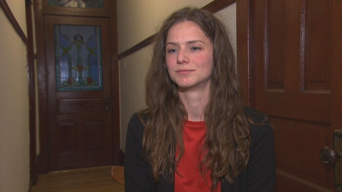Une femme habillée professionnellement dans le corridor d'un appartement.