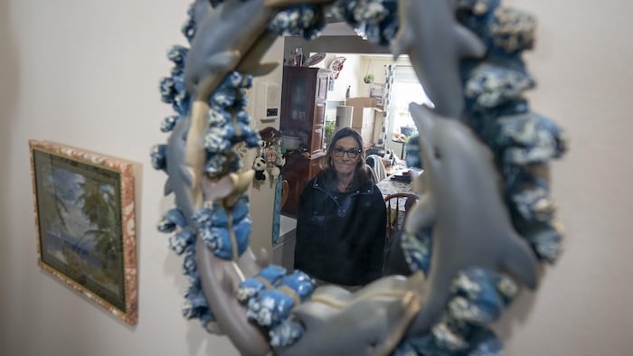 Une dame regarde son propre reflet dans un miroir.