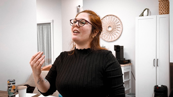 Une femme fait de grands gestes pour diriger des choristes. 