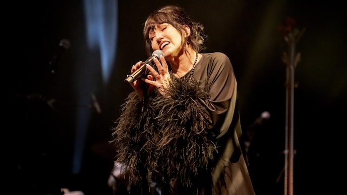 Une femme chante dans un micro sur scène.
