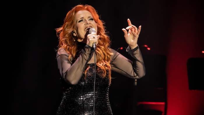 Un femme sur scène chante dans un micro.