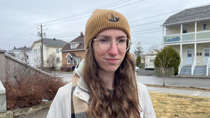 Une femme dans la mi-trentaine avec une tuque et des lunettes.