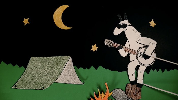 Le lama Viejo Mundo joue de son banjo, perché sur une buche, près d'un feu de camp.