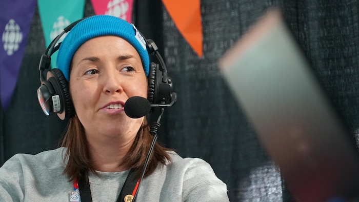 Une femme portant une tuque et un micro-casque en entrevue.